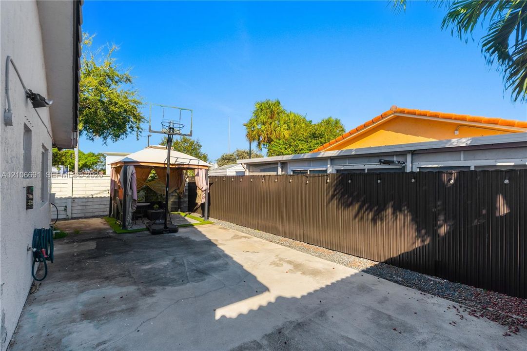 Concrete patio featuring a perimeter fence with corrugated metal panels and a masonry wall border