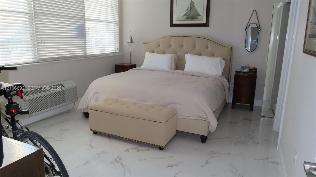 Large-format polished tile flooring featuring a veined stone pattern and expansive window banks with integrated horizontal blinds