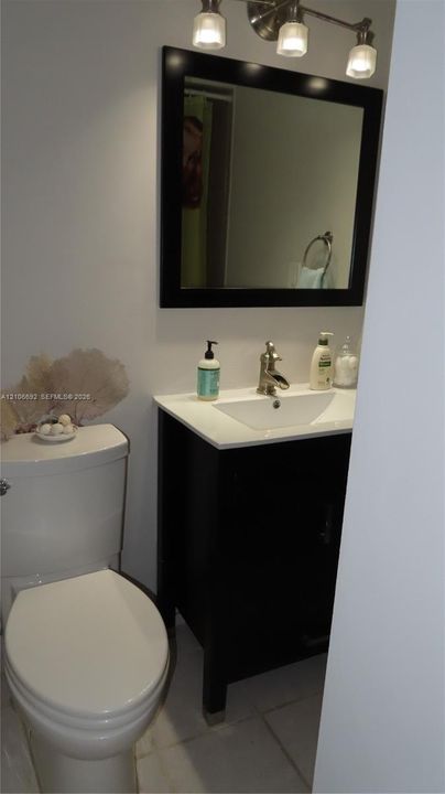 Dark-finish vanity with a rectangular sink, stone-composite countertop, matching framed mirror, and brushed-nickel faucet fixture