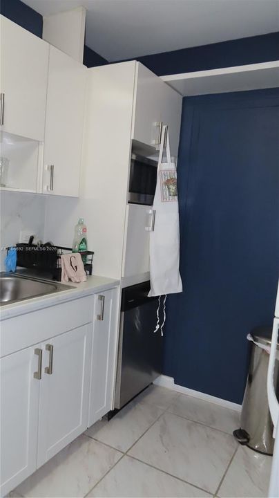 Kitchen featuring white cabinetry, stainless steel dishwasher, built-in microwave, stone-finish countertops, and tile flooring