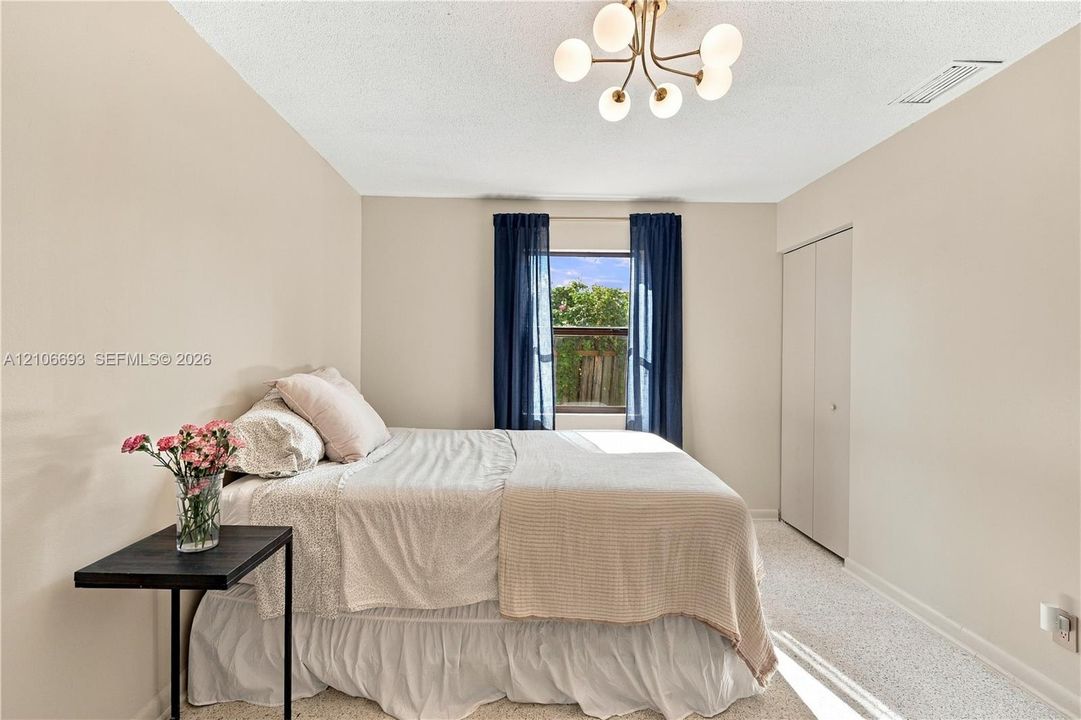Neutral-toned walls, multi-arm light fixture with frosted glass globes, carpeted flooring, and reach-in closet with double doors