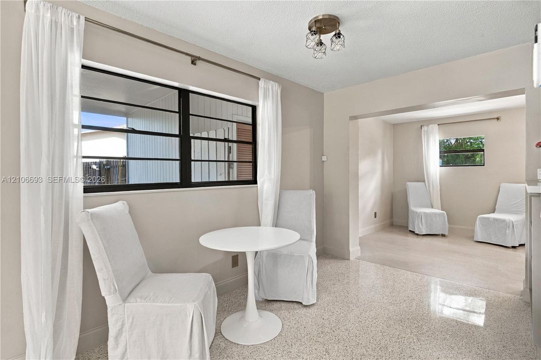 Neutral wall finishes, multi-lite horizontal sliding windows with dark framing, polished aggregate flooring, and a three-light semi-flush mount fixture