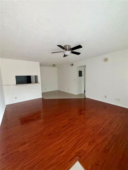 Interior space featuring wood-finish flooring, a ceiling fan with integrated lighting, and a pass-through window with a ledge