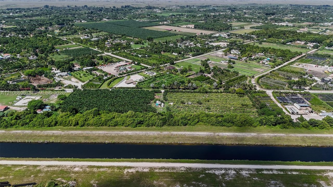 Aerial perspective featuring expansive acreage, mature tree clusters, and irrigation canal frontage