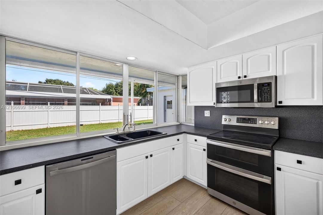 Open concept kitchen w/ updated plank wood look tile, stainless appliances approx 2020
