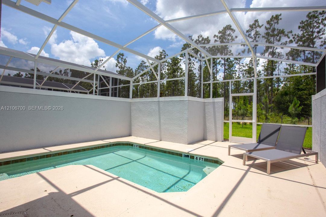 Screen-enclosed swimming pool featuring a concrete deck and stucco privacy walls