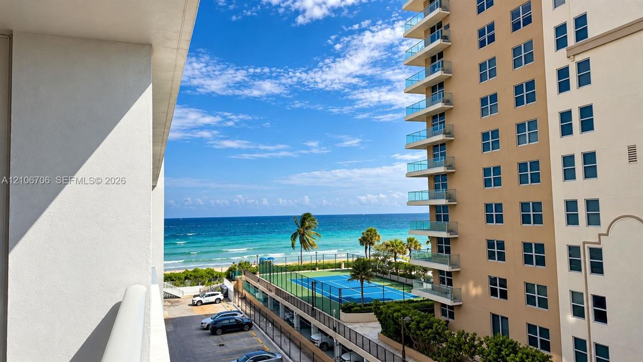 High-rise balcony overlooking the ocean, tennis court, and shoreline