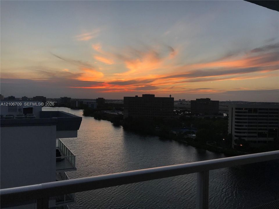 Elevated balcony with a horizontal railing overlooking a waterway and the horizon at dusk