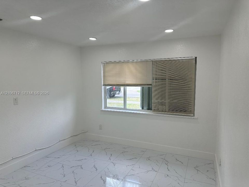 Neutral-toned interior featuring white-finish walls, polished tile flooring with a marble-style pattern, and recessed ceiling lighting