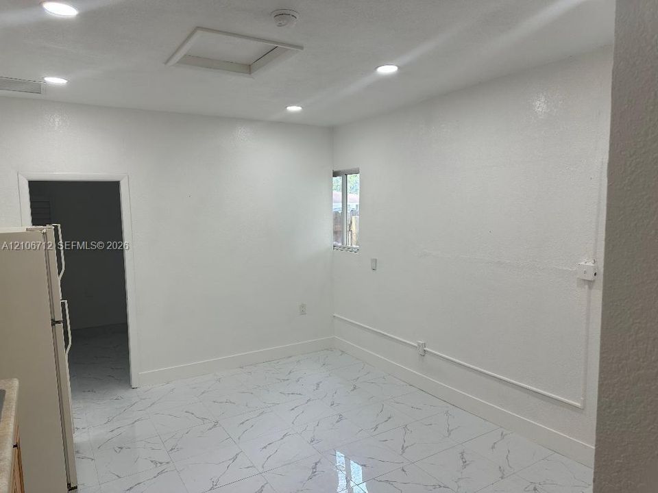 Interior space featuring white stone-finish floor tiles, recessed ceiling lighting, and smooth-finish walls