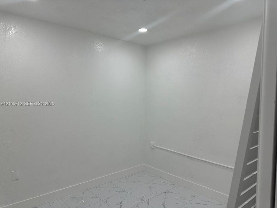 Interior space featuring neutral wall finishes, stone-style tile flooring, and integrated recessed lighting