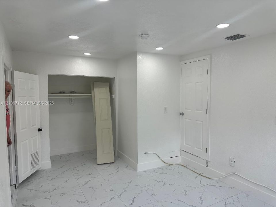 Interior space featuring large-format tile flooring with a light veined pattern, recessed ceiling lighting, and a reach-in closet with integrated shelving