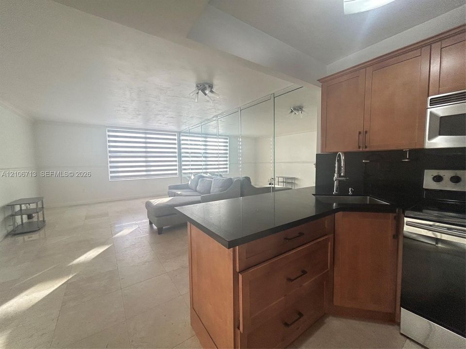 Kitchen featuring wood-finish cabinetry, solid surface countertops, stainless steel appliances, and large-format tile flooring