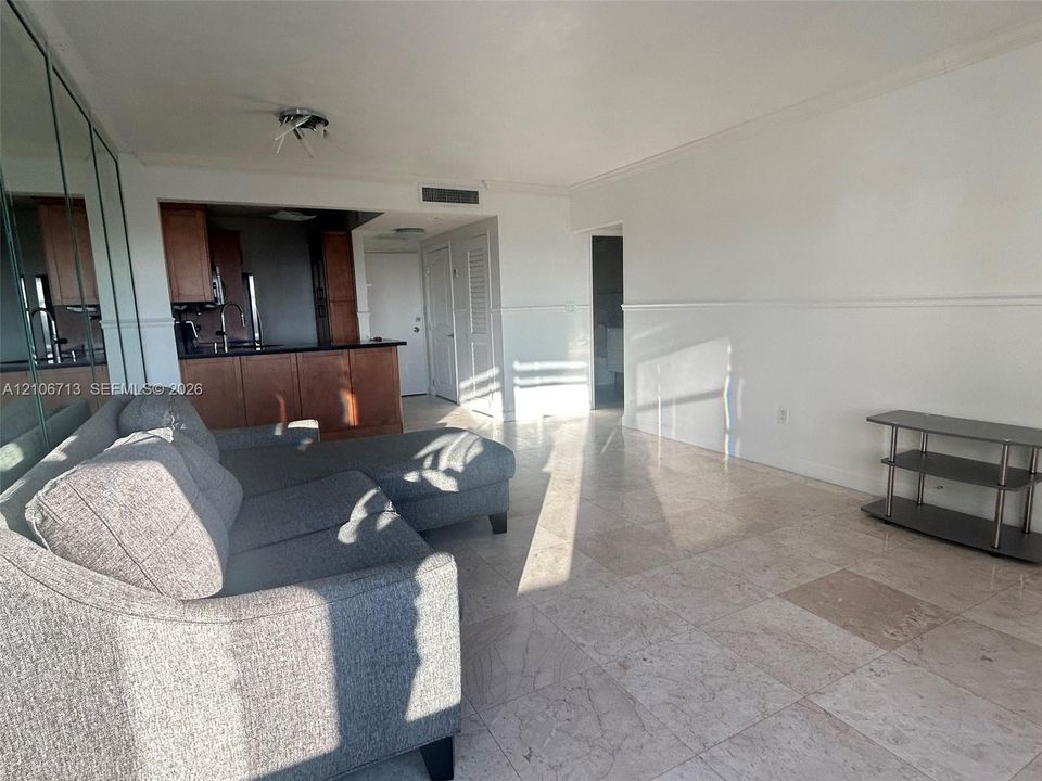 Large-format light-colored stone flooring, mirrored wall paneling, crown molding, chair rail trim, and dark-toned cabinetry with a peninsula counter