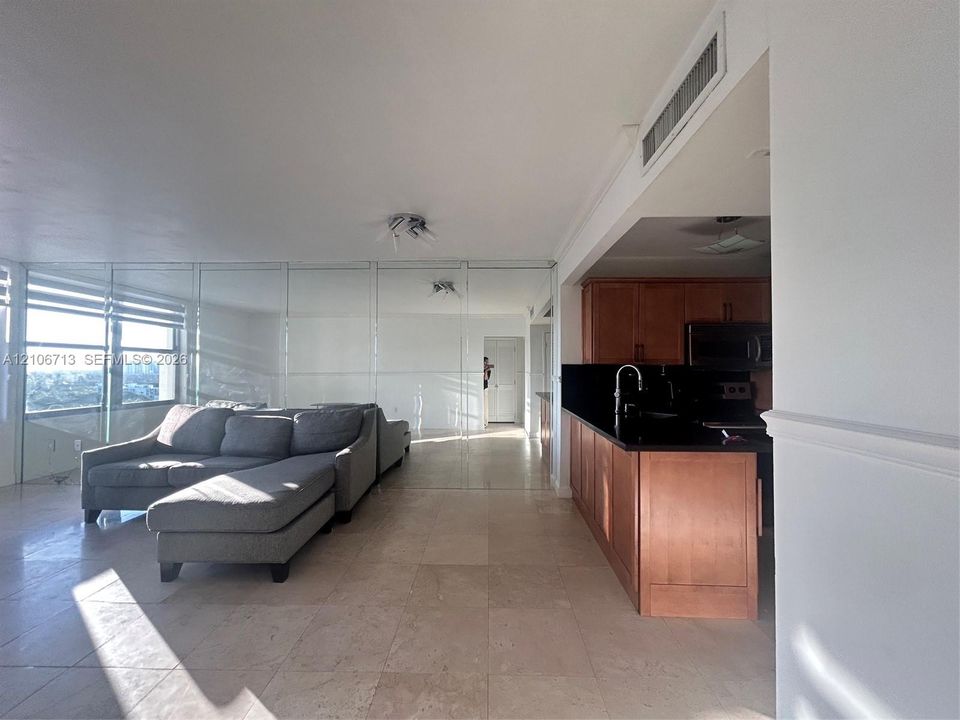 Open-concept floor plan featuring light-toned tile flooring, floor-to-ceiling mirrored walls, and expansive windows