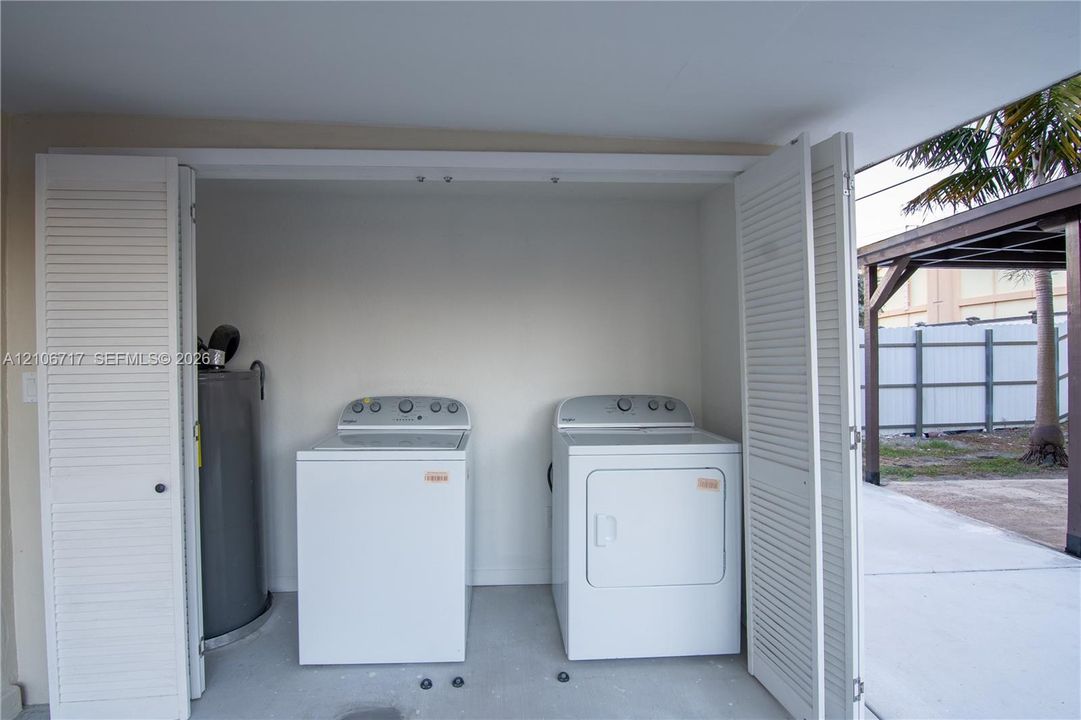 Laundry area featuring bi-fold louvered doors, white appliances, and a cylindrical water heater
