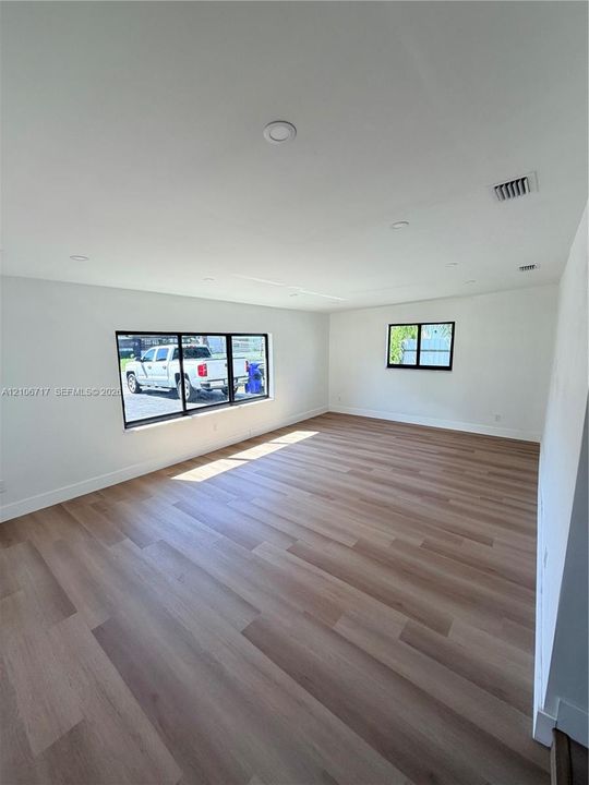 Interior space featuring light-toned wood-finish flooring, recessed lighting, and black-framed windows