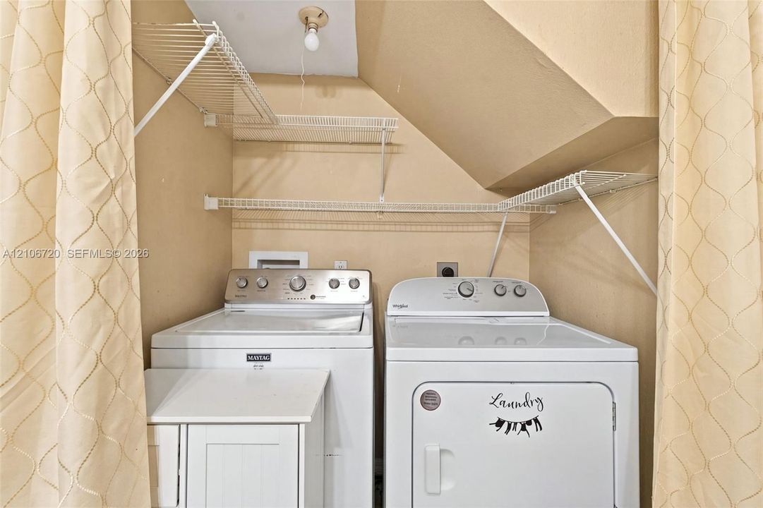 Laundry area featuring white wire shelving, a ceiling-mounted light fixture, and a built-in white cabinet unit