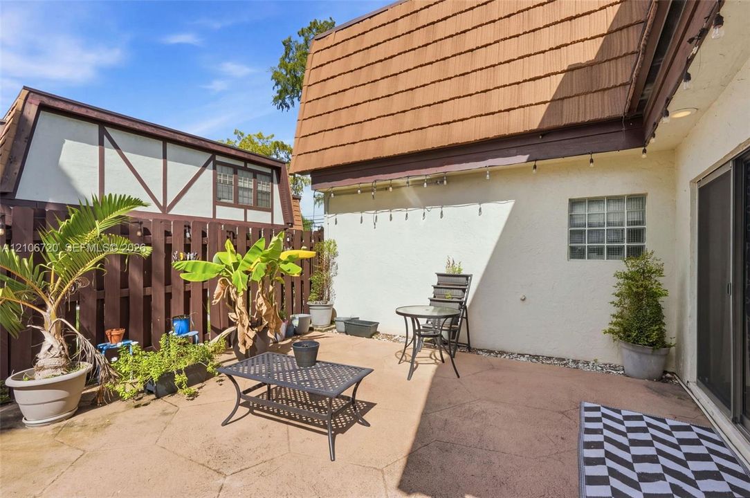 Private rear patio featuring stamped concrete flooring, a block wall fence, and a glass block window