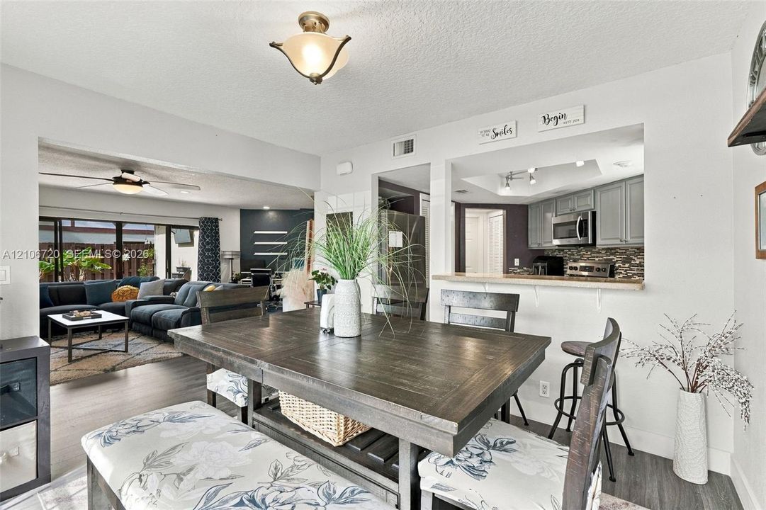 Dining area featuring wood-finish flooring, a pass-through opening to the kitchen, and a flush-mount light fixture