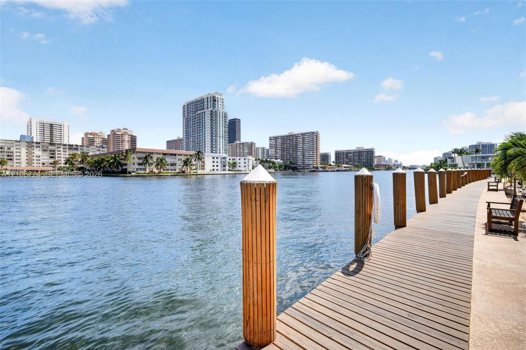 Waterfront wooden dock featuring rounded pilings and a concrete walkway