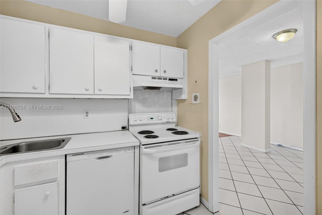 Kitchen featuring white cabinetry, solid-surface countertops, integrated stainless steel sink with gooseneck faucet, white electric range, and dishwasher