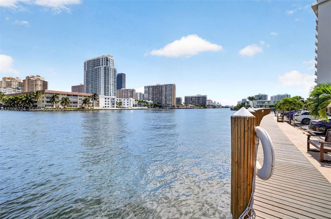Waterfront property featuring a wooden bulkhead with pilings and a paved walkway