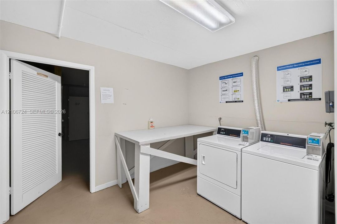 Utility room featuring built-in white folding table, louvered door, and overhead fluorescent lighting