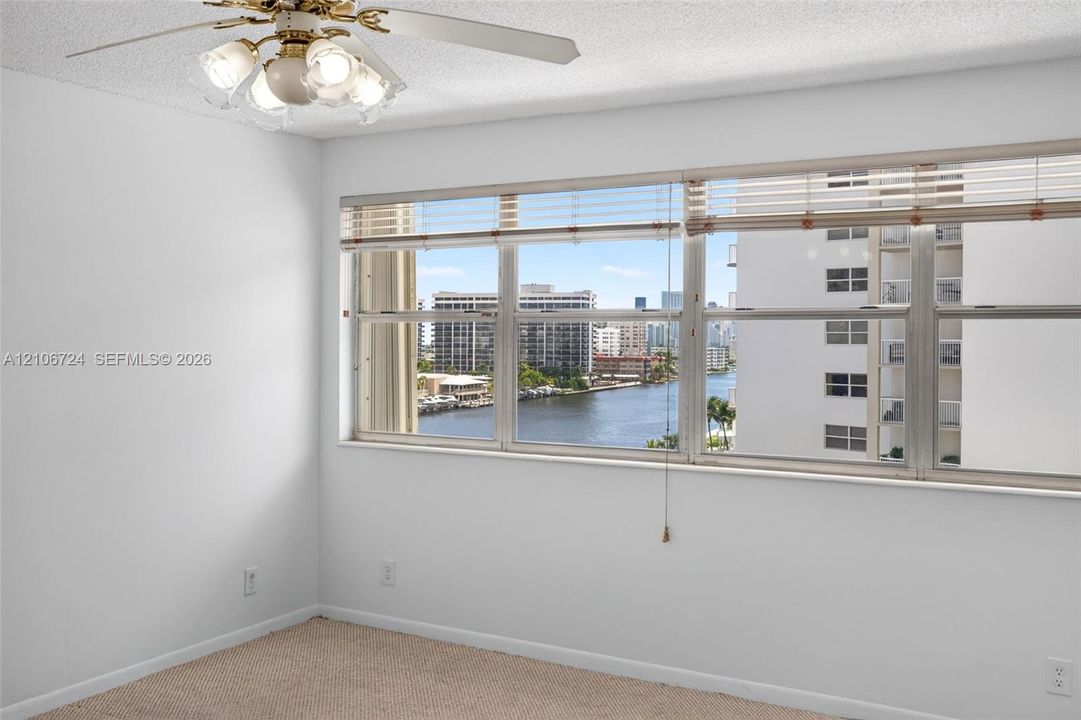 Large windows with horizontal blinds, carpeted flooring, and a ceiling fan with integrated lighting fixtures
