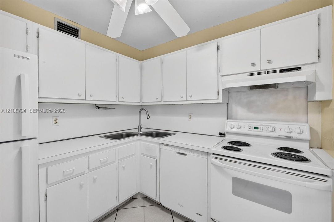 Kitchen featuring white cabinetry, solid-surface countertops, dual-basin sink with a gooseneck faucet, integrated dishwasher, and electric range