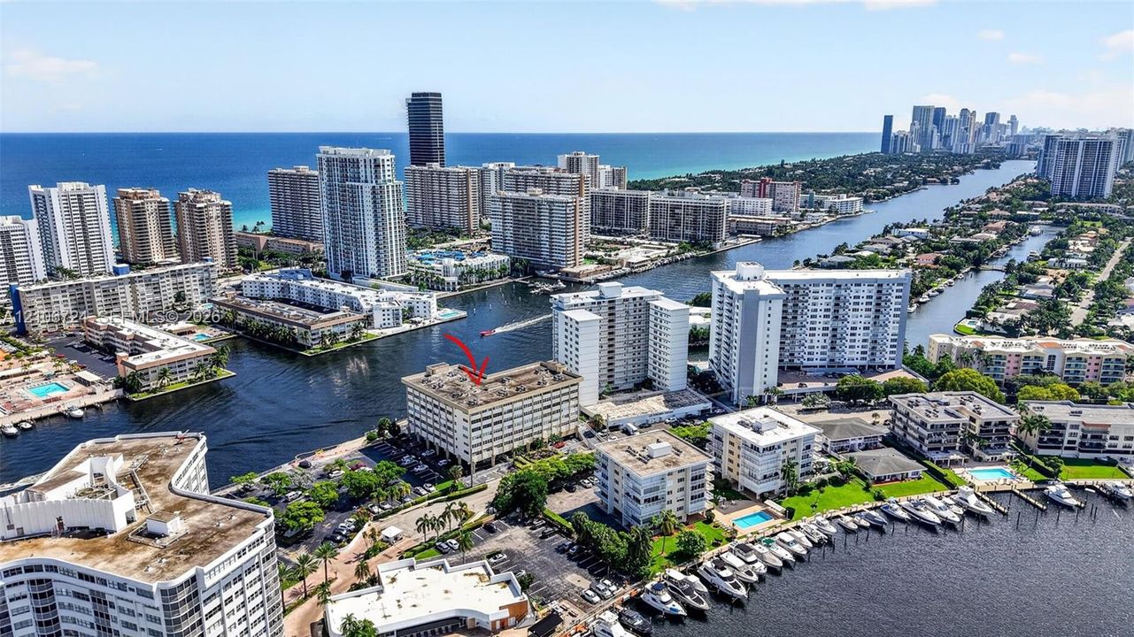 Aerial perspective of a multi-story waterfront building featuring direct canal access, docking facilities, and proximity to the coastline