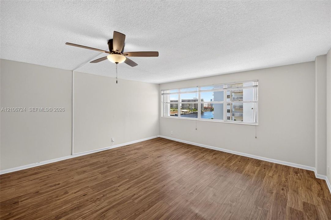 Interior space featuring wood-finish flooring, a multi-pane horizontal window, and a ceiling-mounted fan with integrated lighting