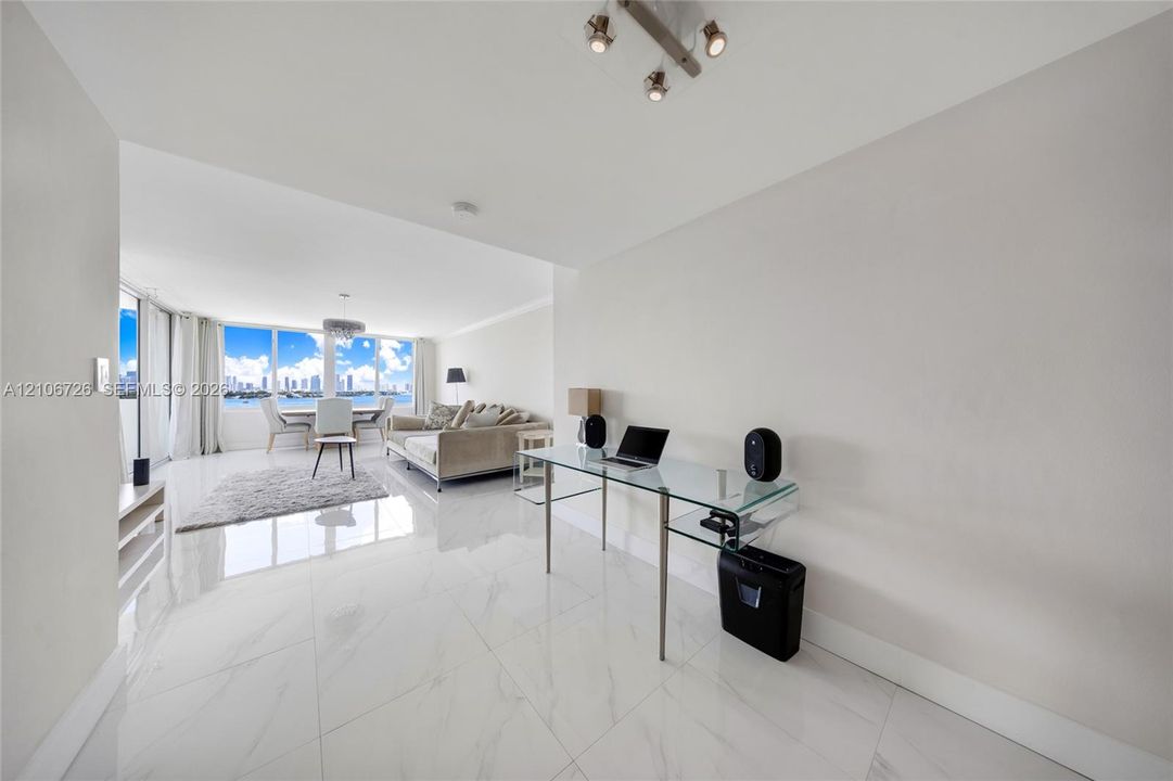 Large-format stone-style tile flooring, floor-to-ceiling windows, and multi-directional overhead track lighting