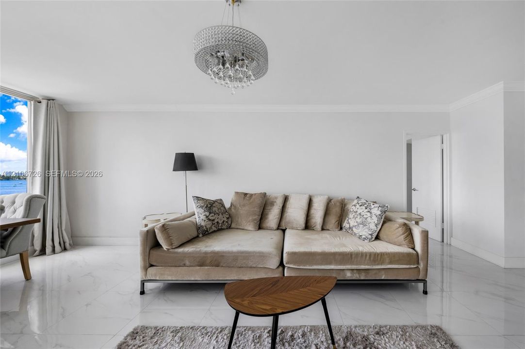 Polished stone flooring, crystal-accented chandelier, and expansive glass paneled window