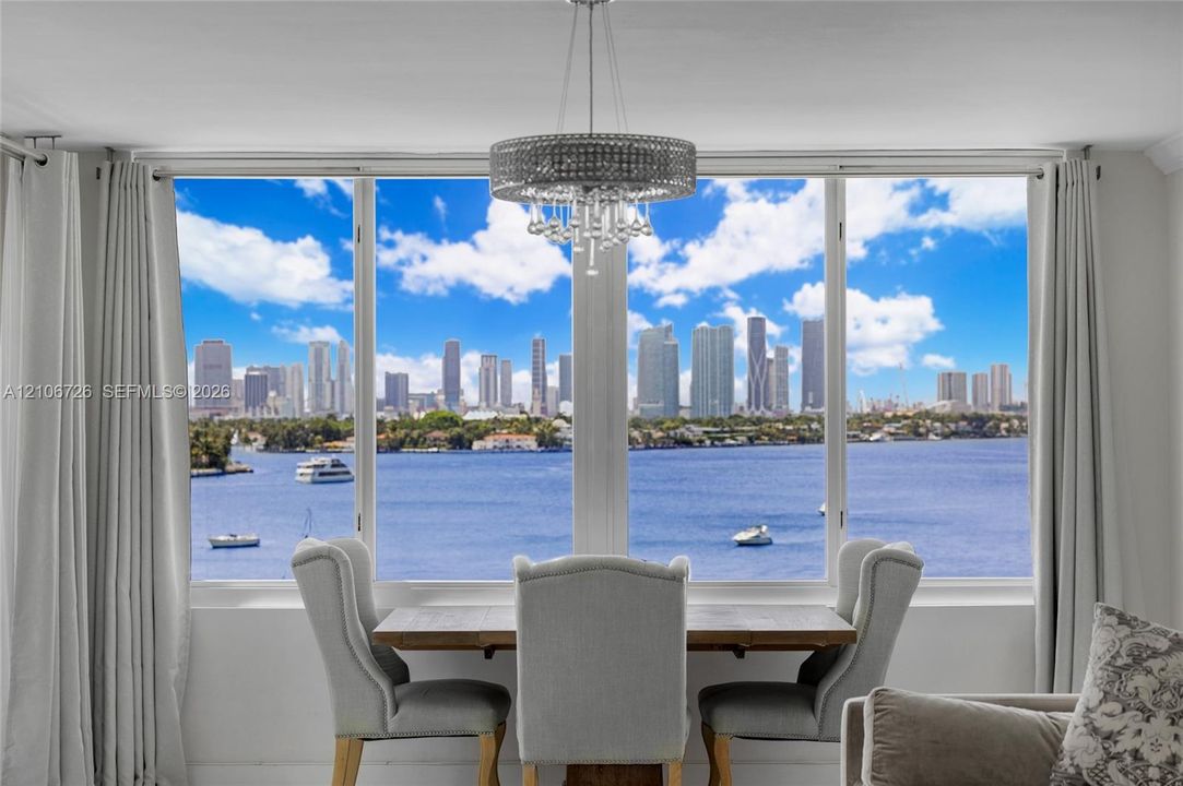 Floor-to-ceiling windows featuring panoramic water and city skyline scenery, complemented by a contemporary circular crystal drum chandelier