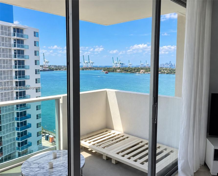 Private balcony featuring floor-to-ceiling glass sliding doors, a glass paneled railing, and water frontage