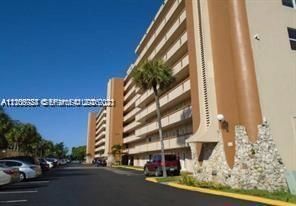 Multi-story exterior featuring integrated balconies, concrete structure with stone accents, and paved surface parking