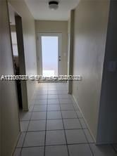 Entryway featuring large-format ceramic tile flooring, neutral wall finishes, and a single-lite glass entry door with a flush-mount ceiling fixture