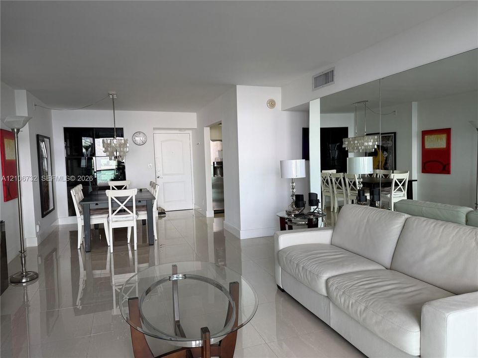 Open-concept interior featuring large-format tile flooring, full-wall mirrors, and a tiered crystal chandelier