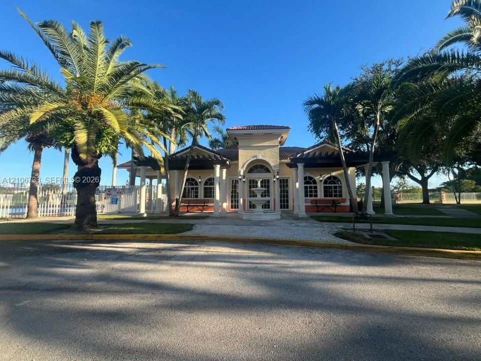 Stucco exterior featuring arched windows, a covered portico with classical columns, a decorative tiered water fountain, and pergola-covered walkways