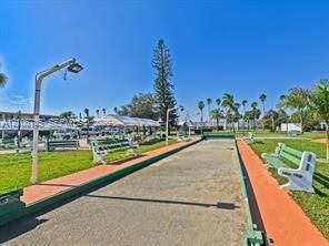 Bocce ball court featuring a crushed stone playing surface, perimeter framing, overhead lighting, and surrounding bench seating