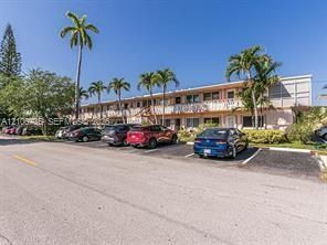 Multi-story exterior featuring a balcony railing system, concrete parking area, and mature palm trees