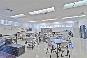 Open-plan interior space featuring high-gloss flooring, recessed panel lighting, extensive horizontal windows, and a built-in dark masonry tiered platform