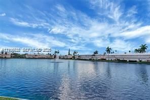 Waterfront lot featuring a wide expanse of water, a central fountain, and surrounding mature palm trees