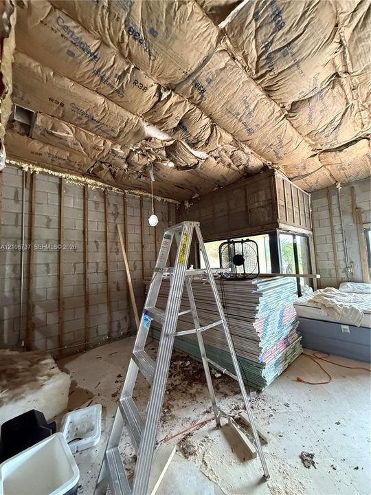 Interior space featuring exposed concrete block walls and ceiling insulation