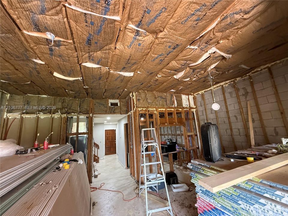 Exposed structural framing featuring concrete block masonry, wood stud wall construction, and ceiling-installed batt insulation