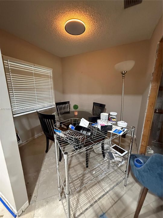Neutral-toned room featuring a window with horizontal blinds, neutral tile flooring, and a circular flush-mount ceiling light