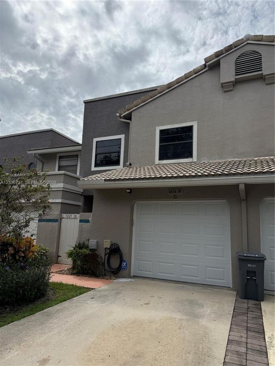 Exterior featuring a stucco facade, tiled roof, attached garage, and paved driveway