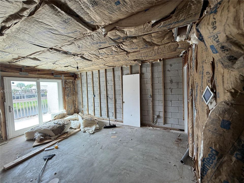 Concrete block wall construction with exposed wall studs, fiberglass batt insulation, and sliding glass door