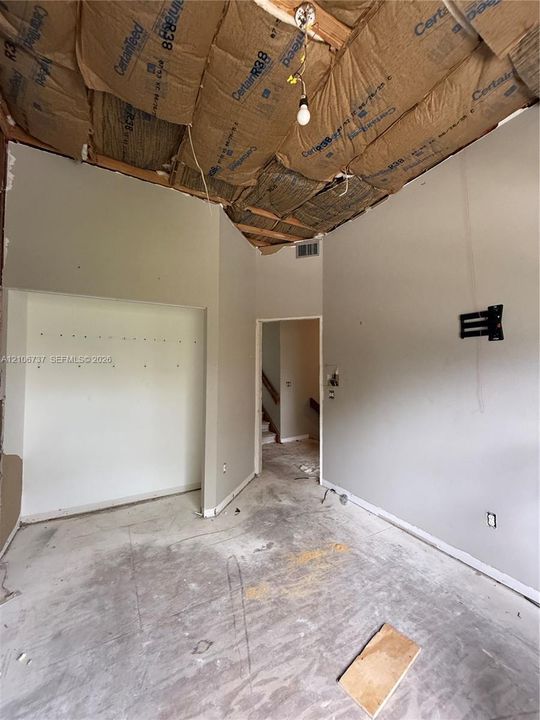 Interior space featuring exposed ceiling insulation, recessed wall niche, and wall-mounted hardware